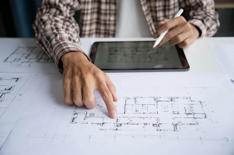 Architekt gleicht Bauzeichnung und Laptopanwendung ab